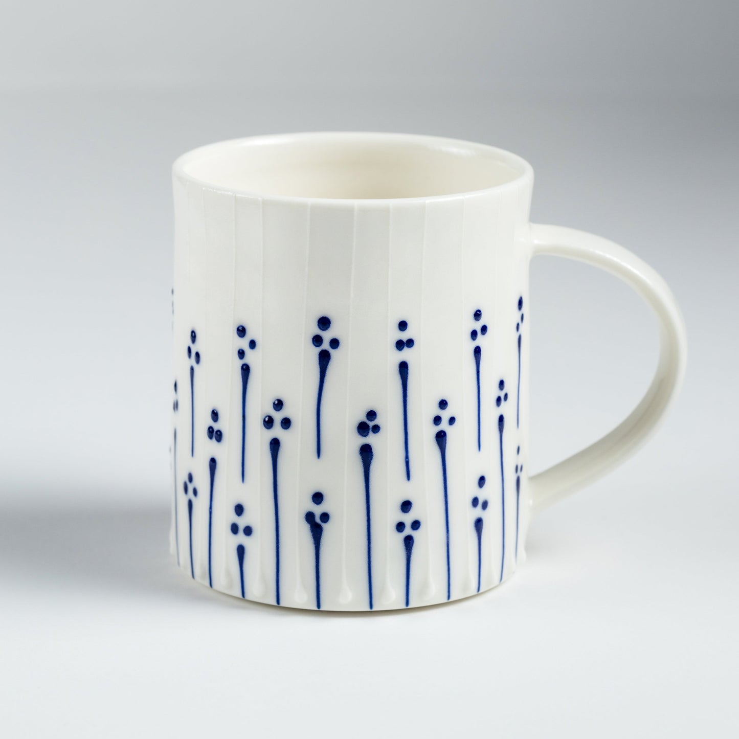 Handmade porcelain tea mug with blue slip-trailed flower pattern