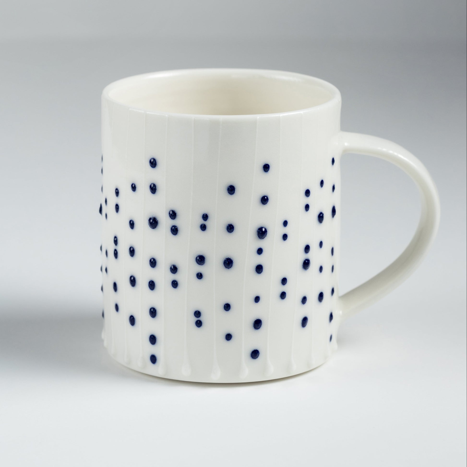 Handmade porcelain tea mug with blue slip-trailed dot pattern