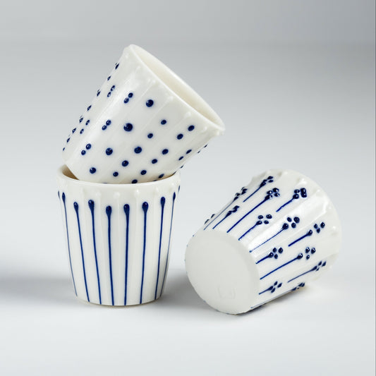 Handmade porcelain egg cups with blue slip-trailed dot, line, and flower patterns