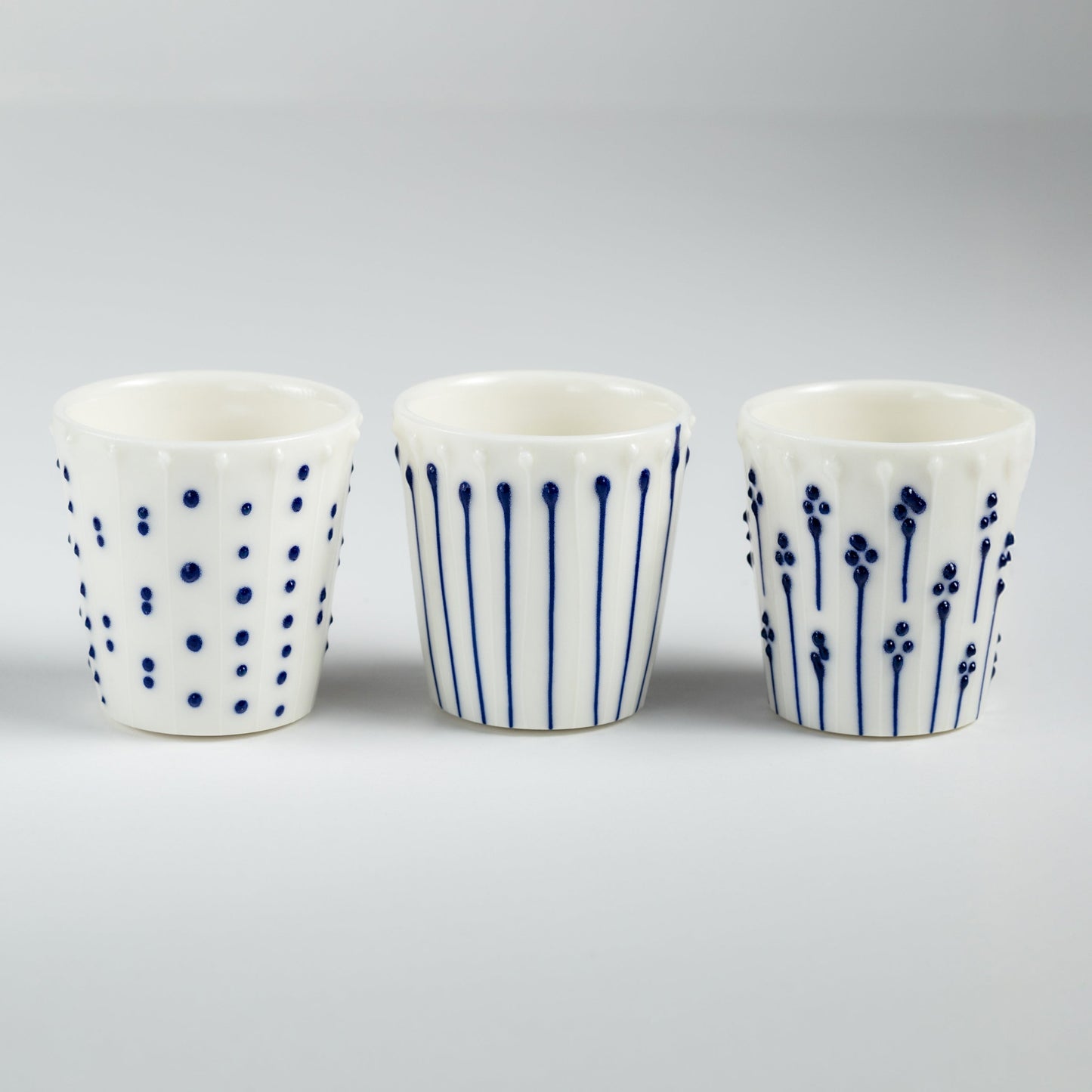 Handmade porcelain egg cups with blue slip-trailed dot, line, and flower patterns