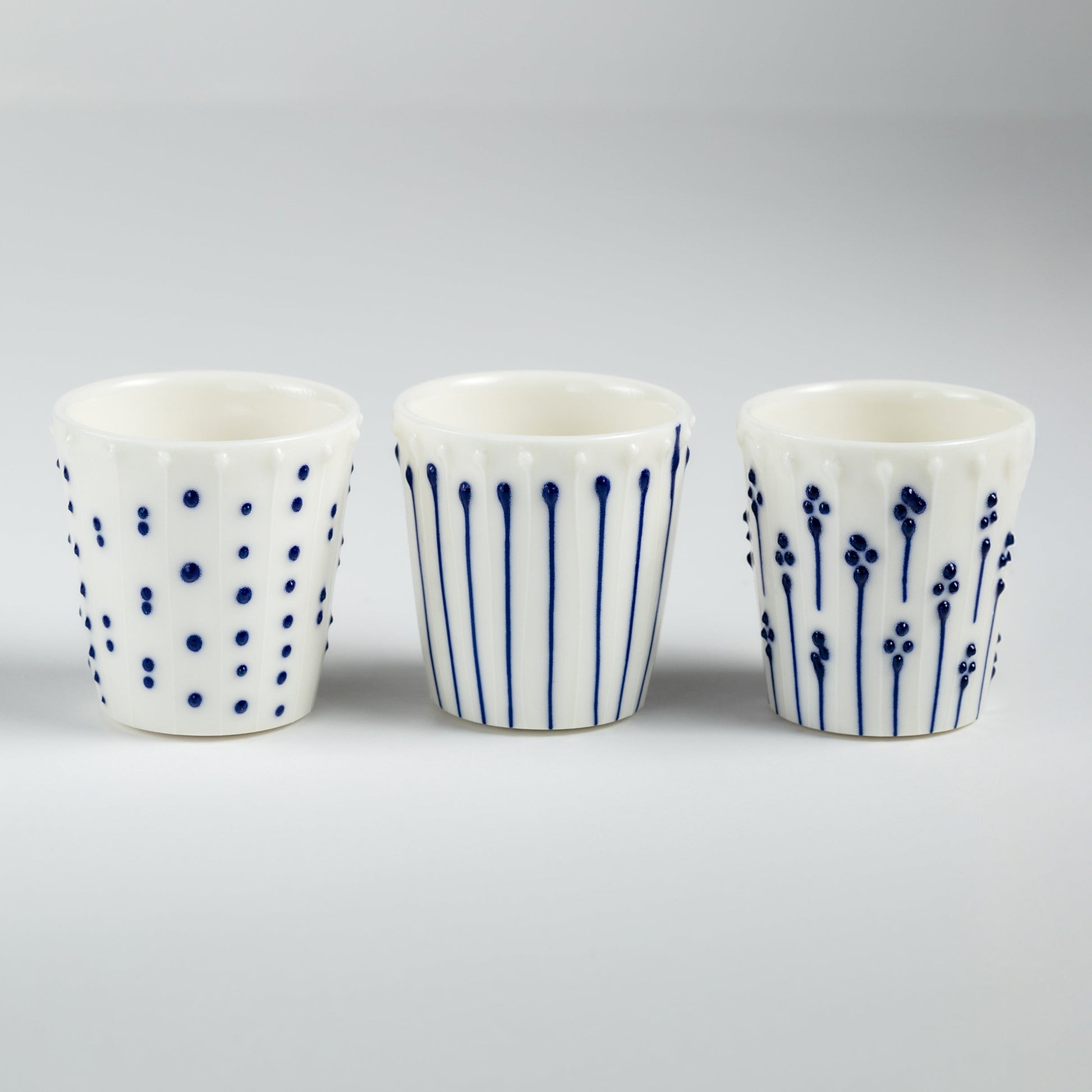 Handmade porcelain egg cups with blue slip-trailed dot, line, and flower patterns