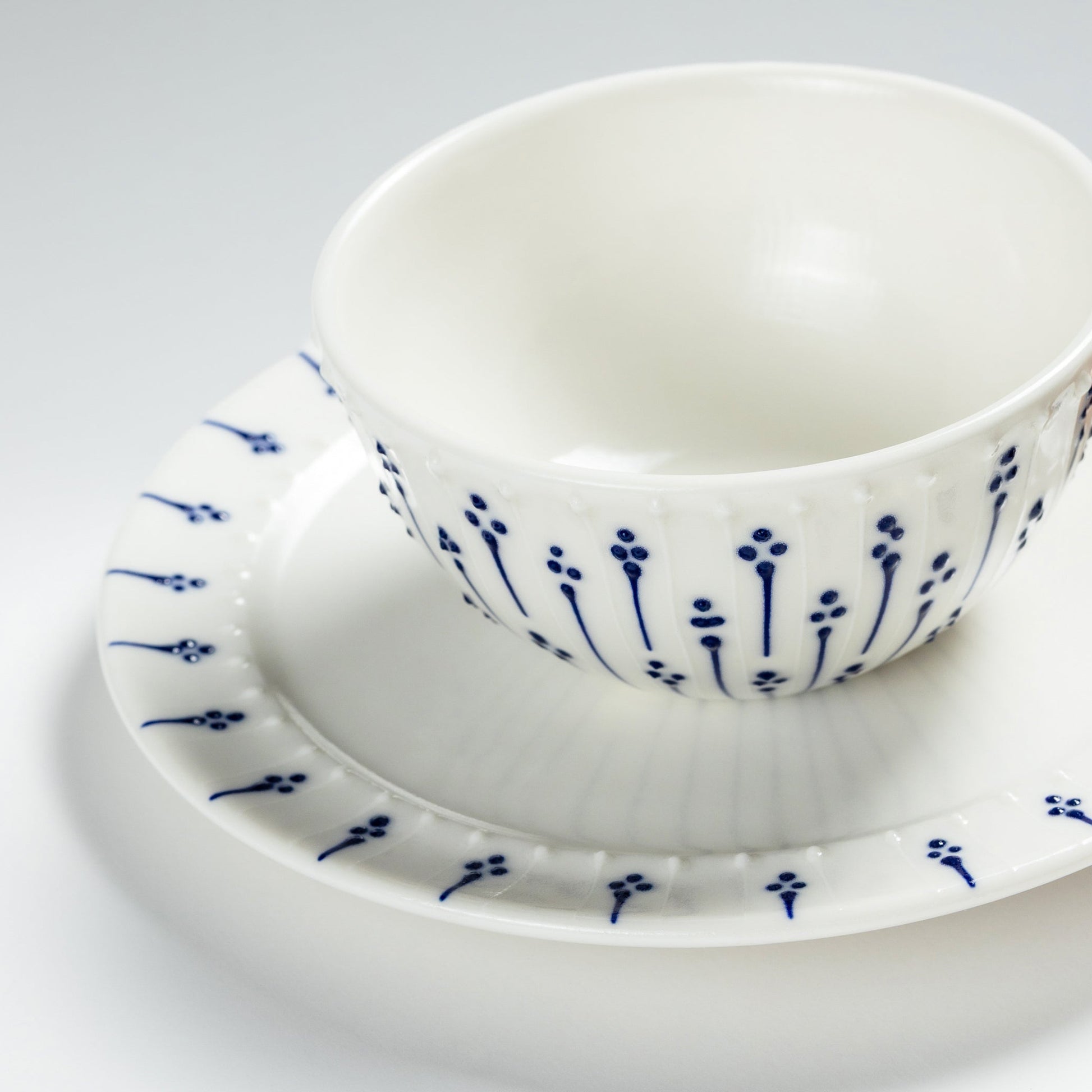 Handmade porcelain side plate with blue floral pattern styled with breakfast bowl
