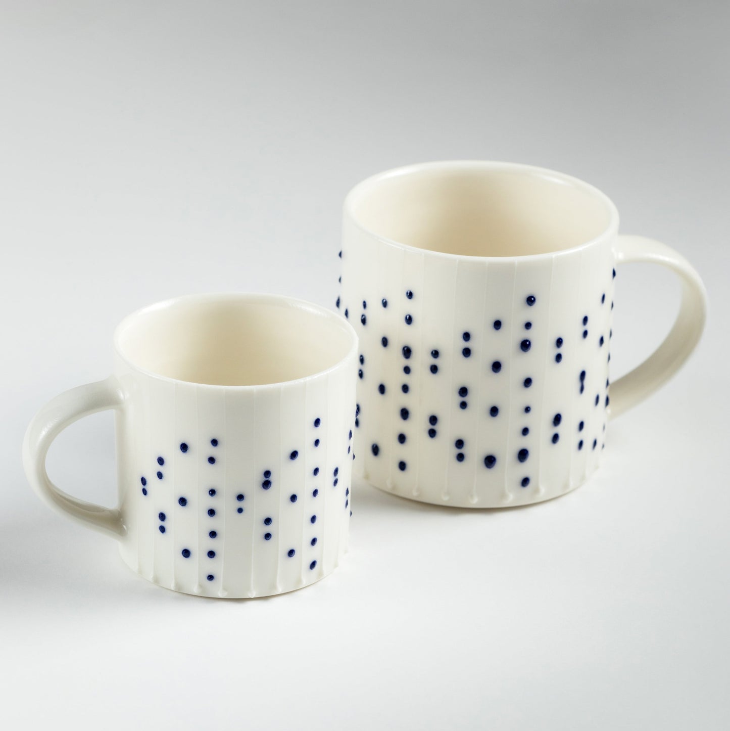 Handmade porcelain coffee mugs with blue slip-trailed dot decoration in two sizes