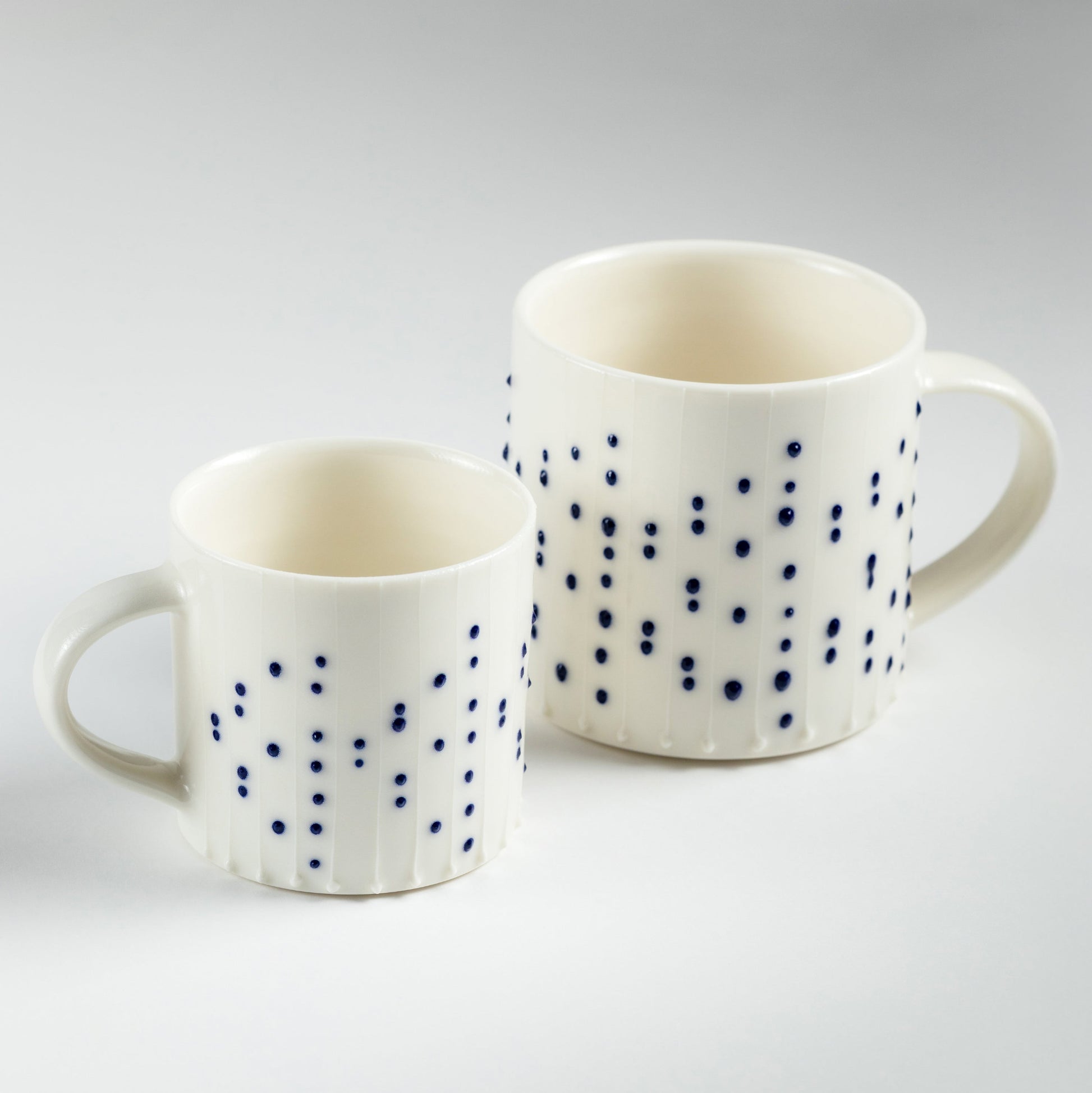 Handmade porcelain coffee mugs with blue slip-trailed dot decoration in two sizes