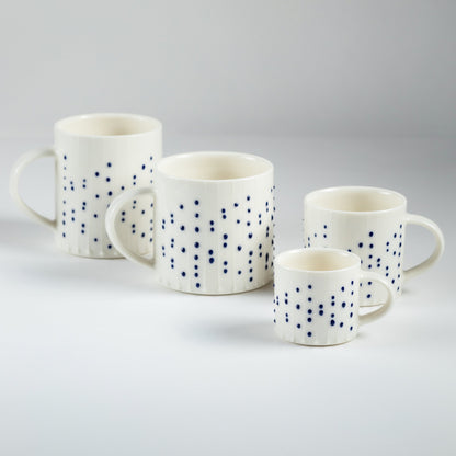 Handmade porcelain mugs in four sizes with blue slip-trailed dot decoration
