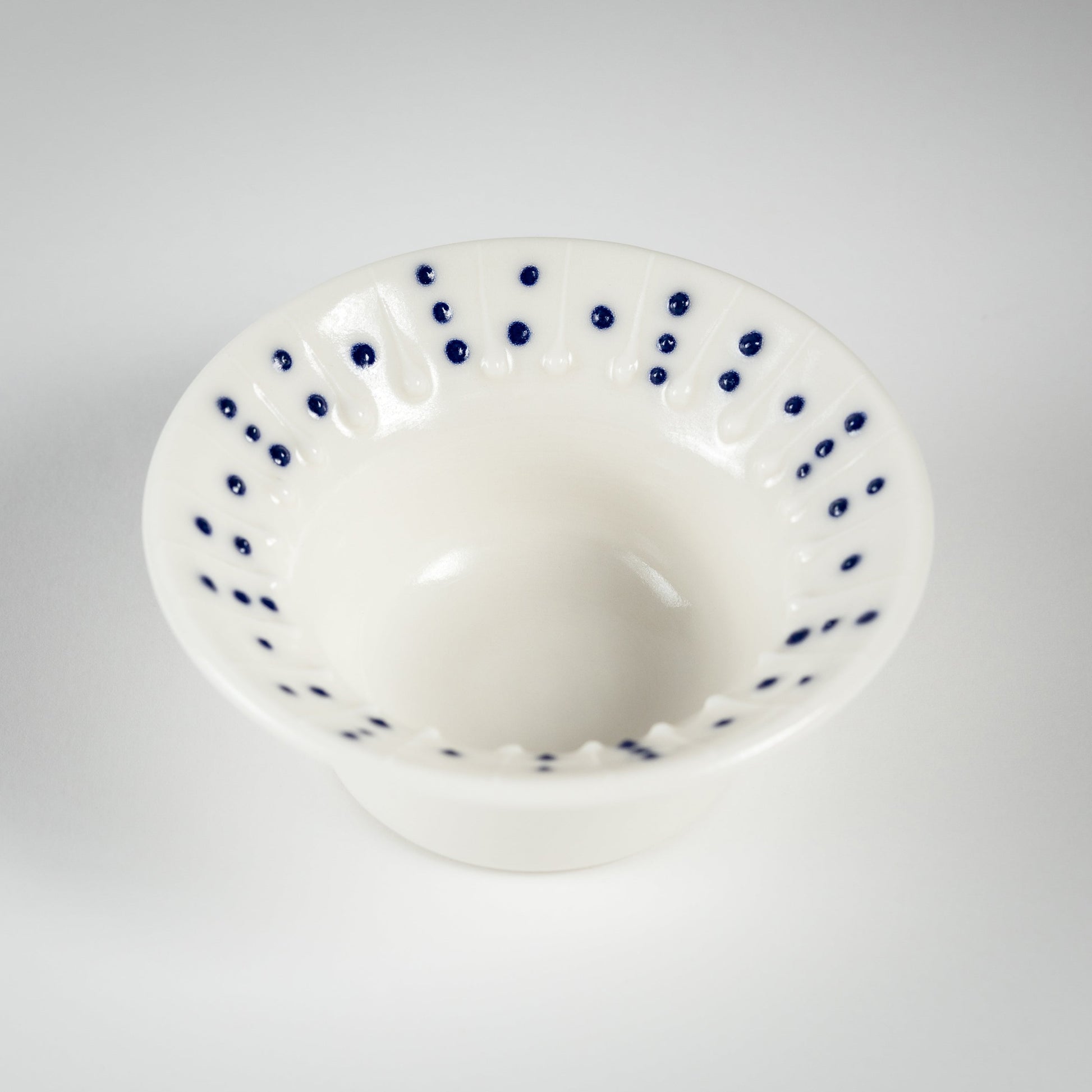 Handmade porcelain tea light holder with flanged rim and blue dotted decoration
