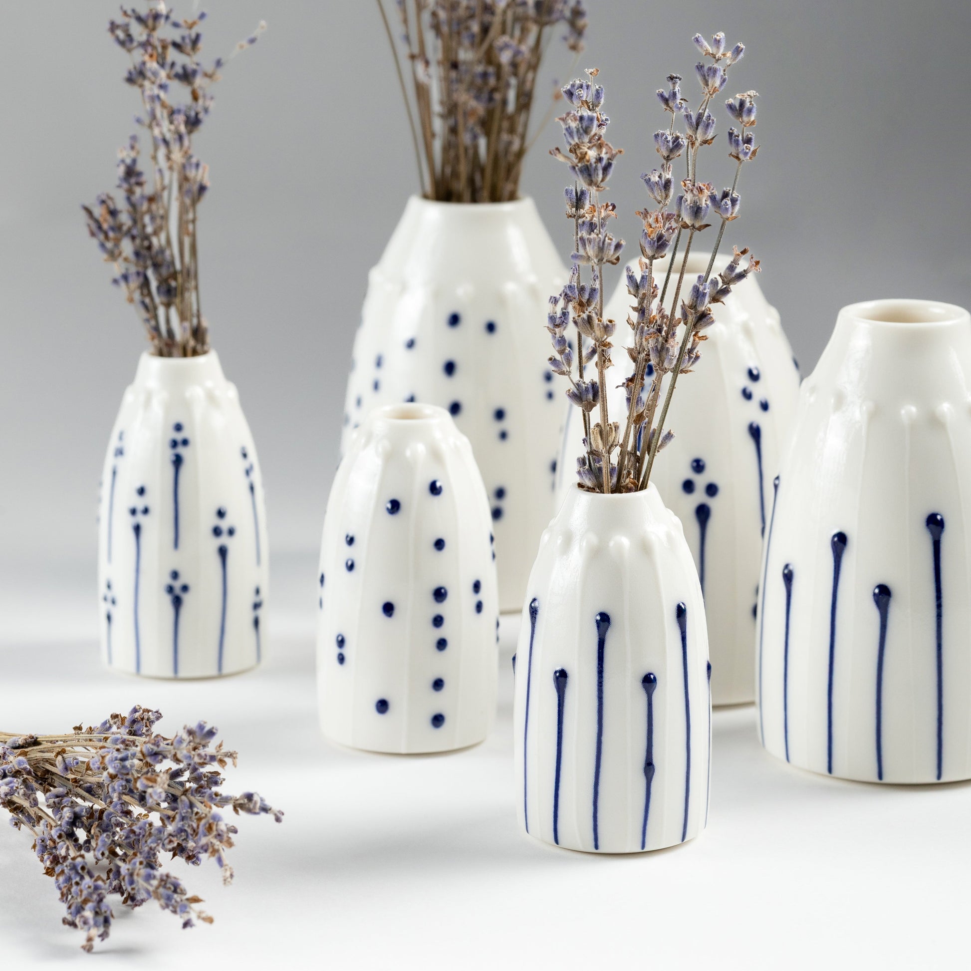 A collection of handmade porcelain mini vases in various blue and white patterns, styled with stems of dried Irish lavender