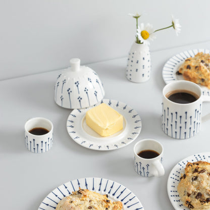 Handmade porcelain breakfast set featuring a blue and white butter dish, espresso cups, and side plates with fresh scones and coffee