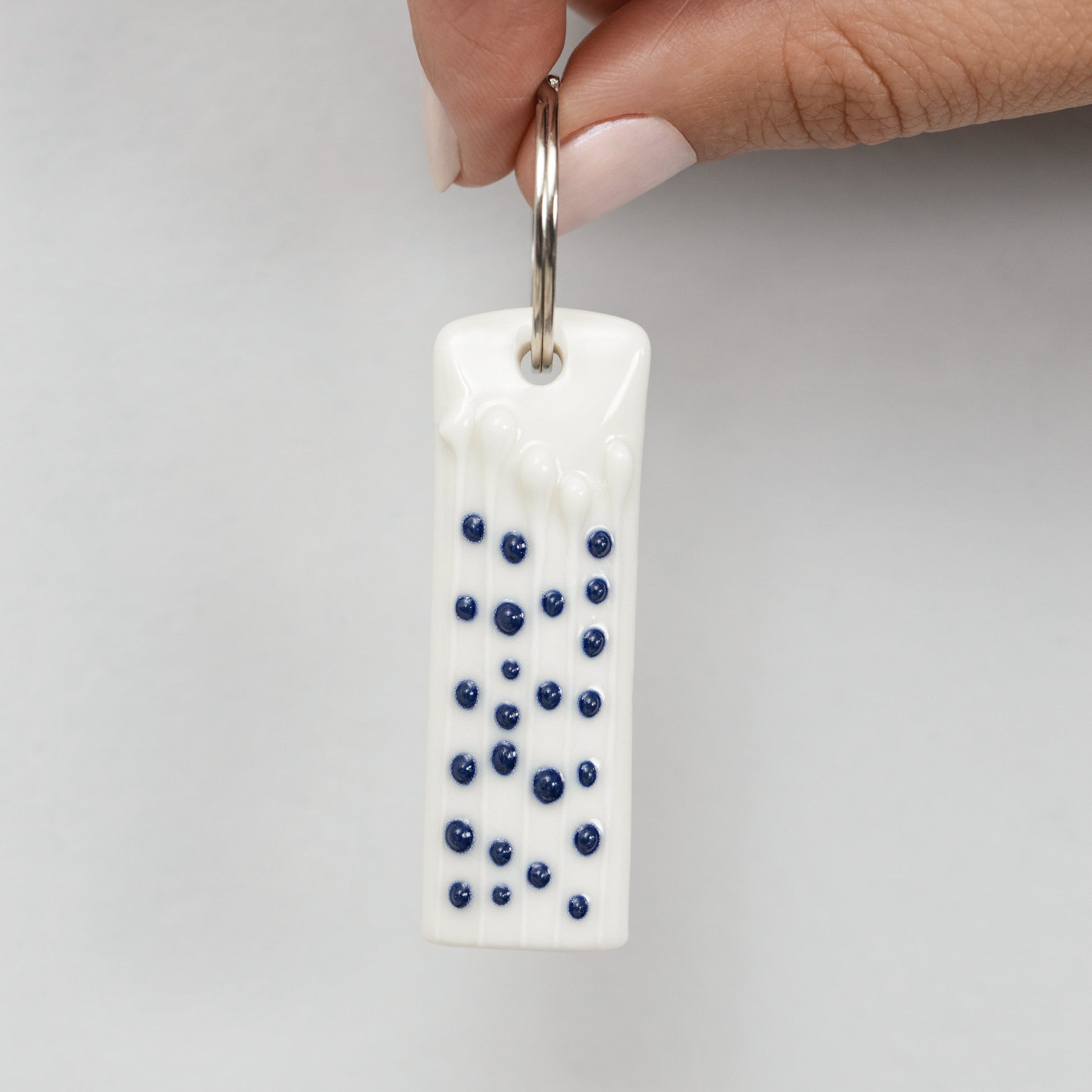 Handmade porcelain mindful charm keyring with blue slip-trailed tactile dotted decoration 