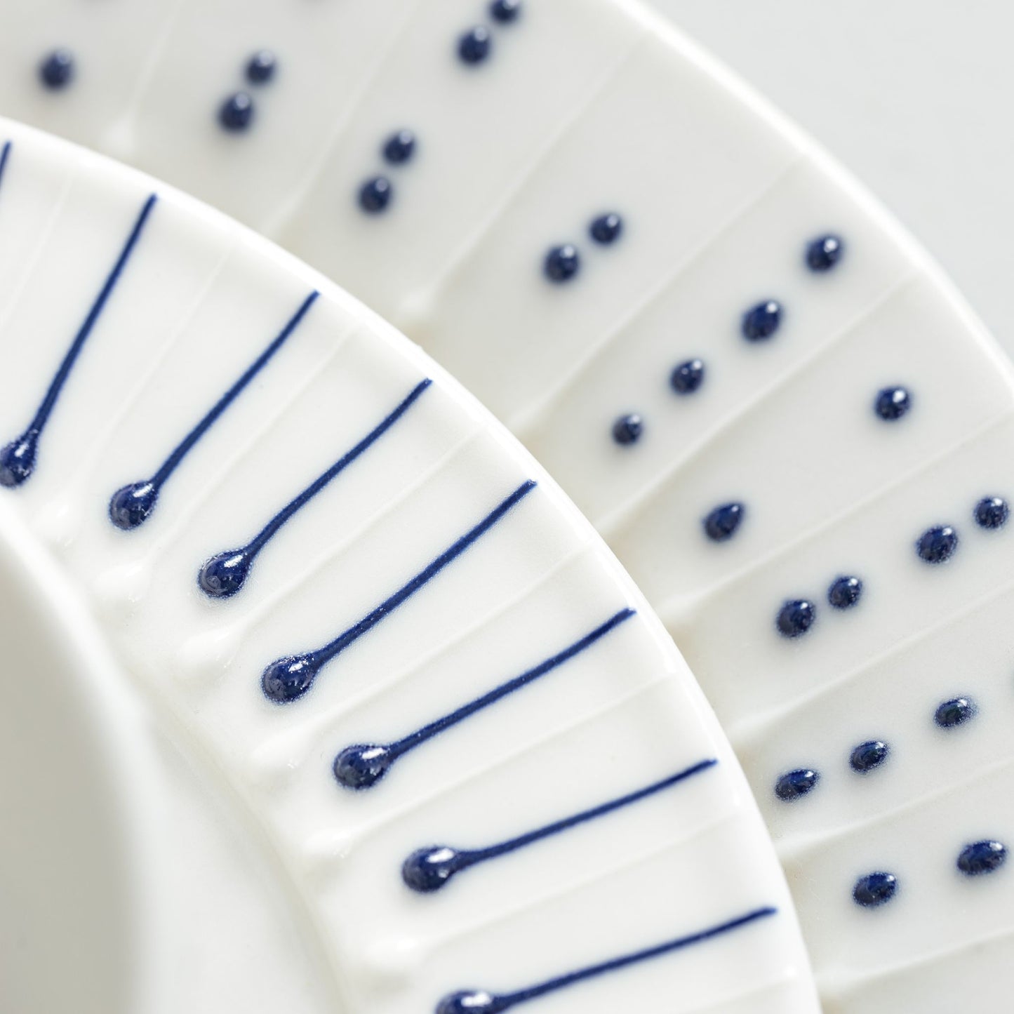 Detail of handmade porcelain side plate with slip-trailed dotted and line patterns