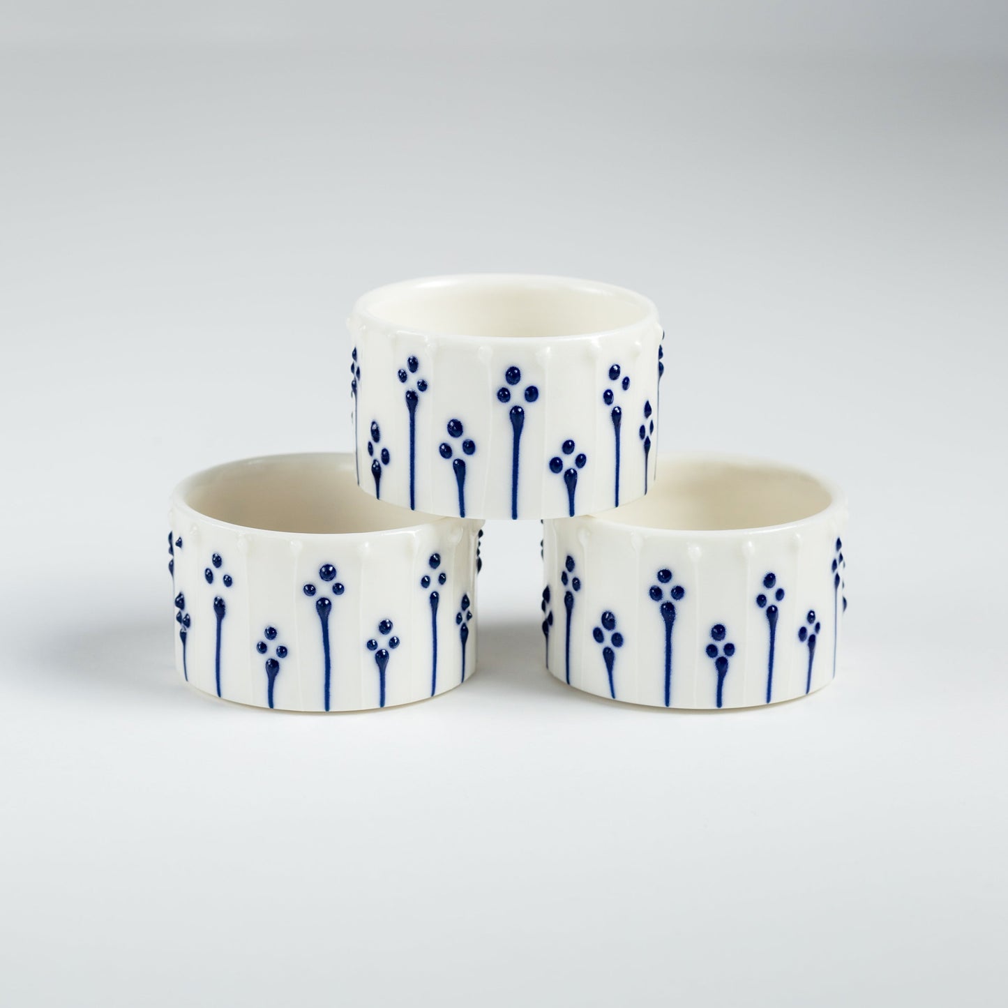 Handmade porcelain tealight holders with blue slip-trailed floral pattern.