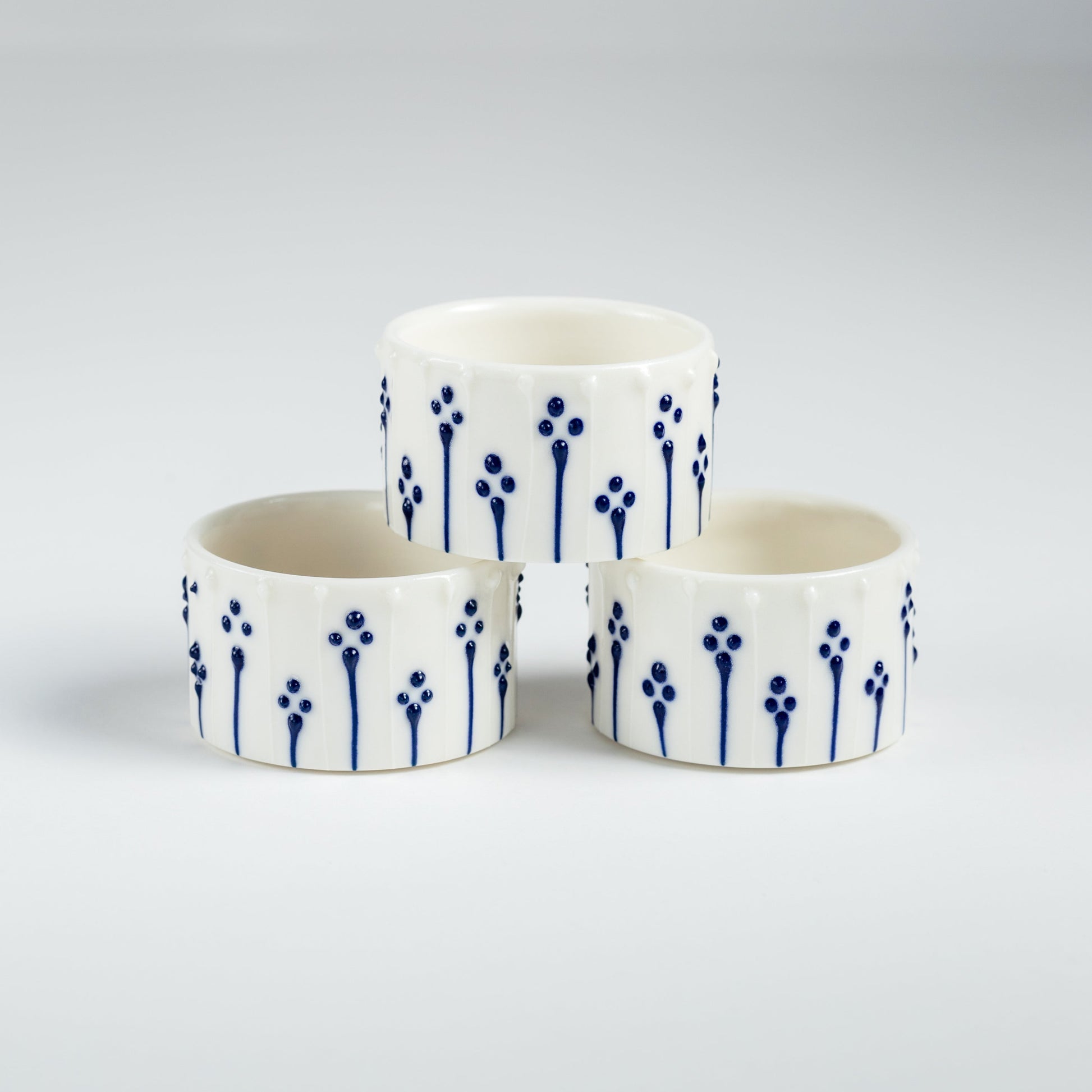 Handmade porcelain tealight holders with blue slip-trailed floral pattern.
