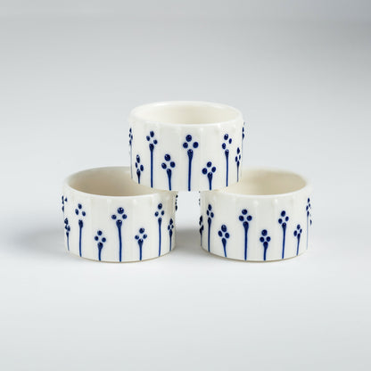 Handmade porcelain tealight holders with blue slip-trailed floral pattern.
