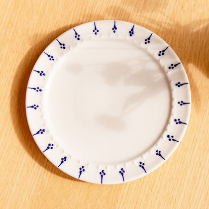 Handmade porcelain side plate with blue flower motif pattern on a wooden table