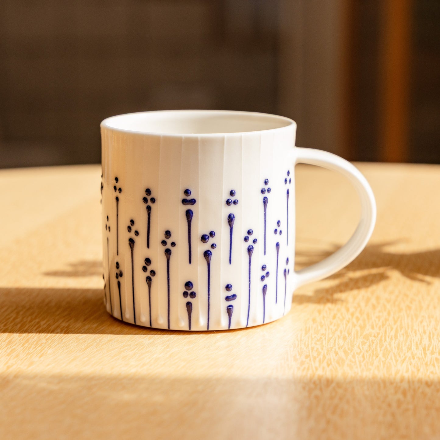Handmade porcelain coffee mug with blue slip-trailed flower pattern