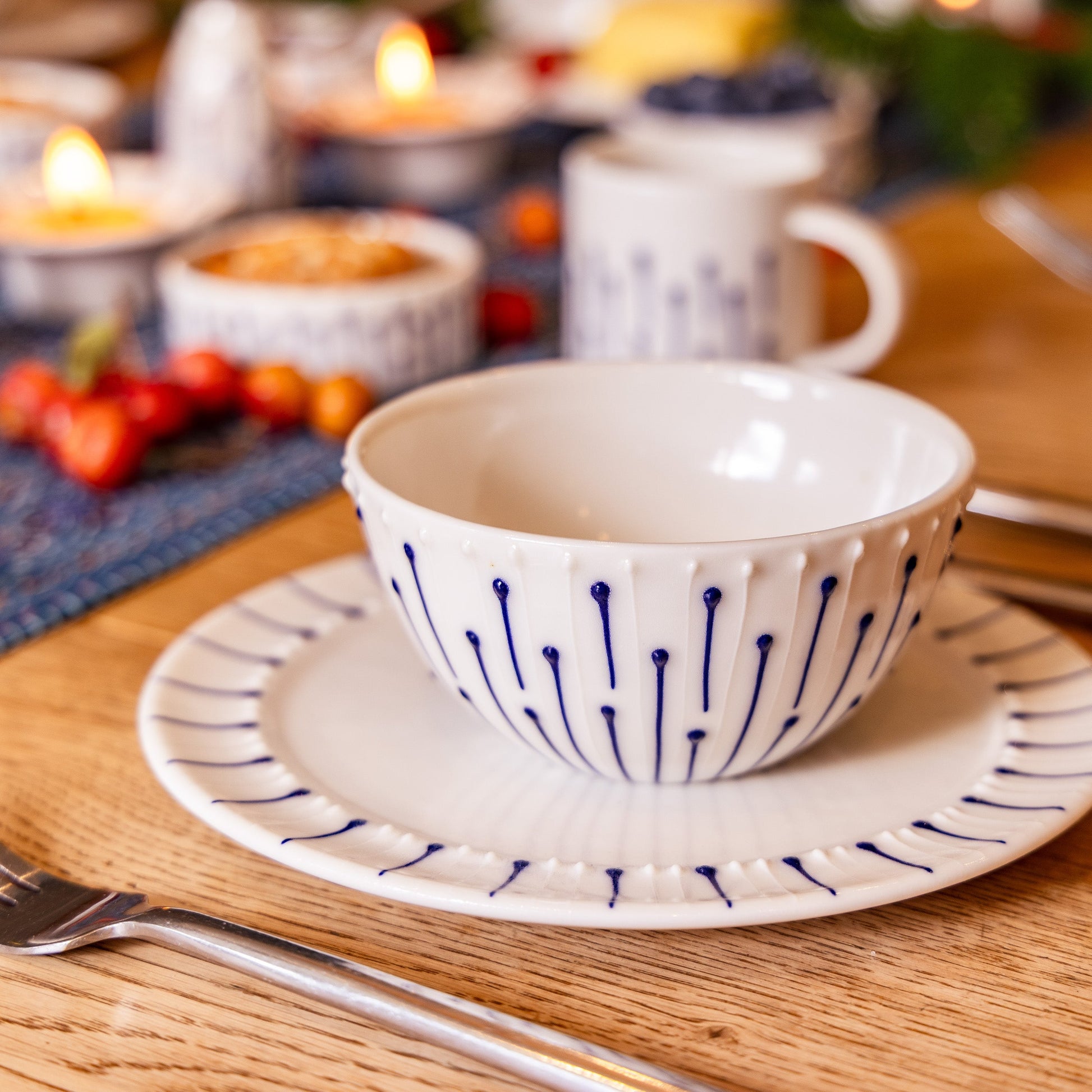 Handmade porcelain breakfast bowl with blue slip-trailed decoration on a matching side plate on a wooden breakfast table
