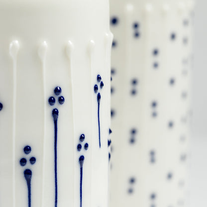 Handmade porcelain tall milk pourer with blue slip-trailed flower pattern close up