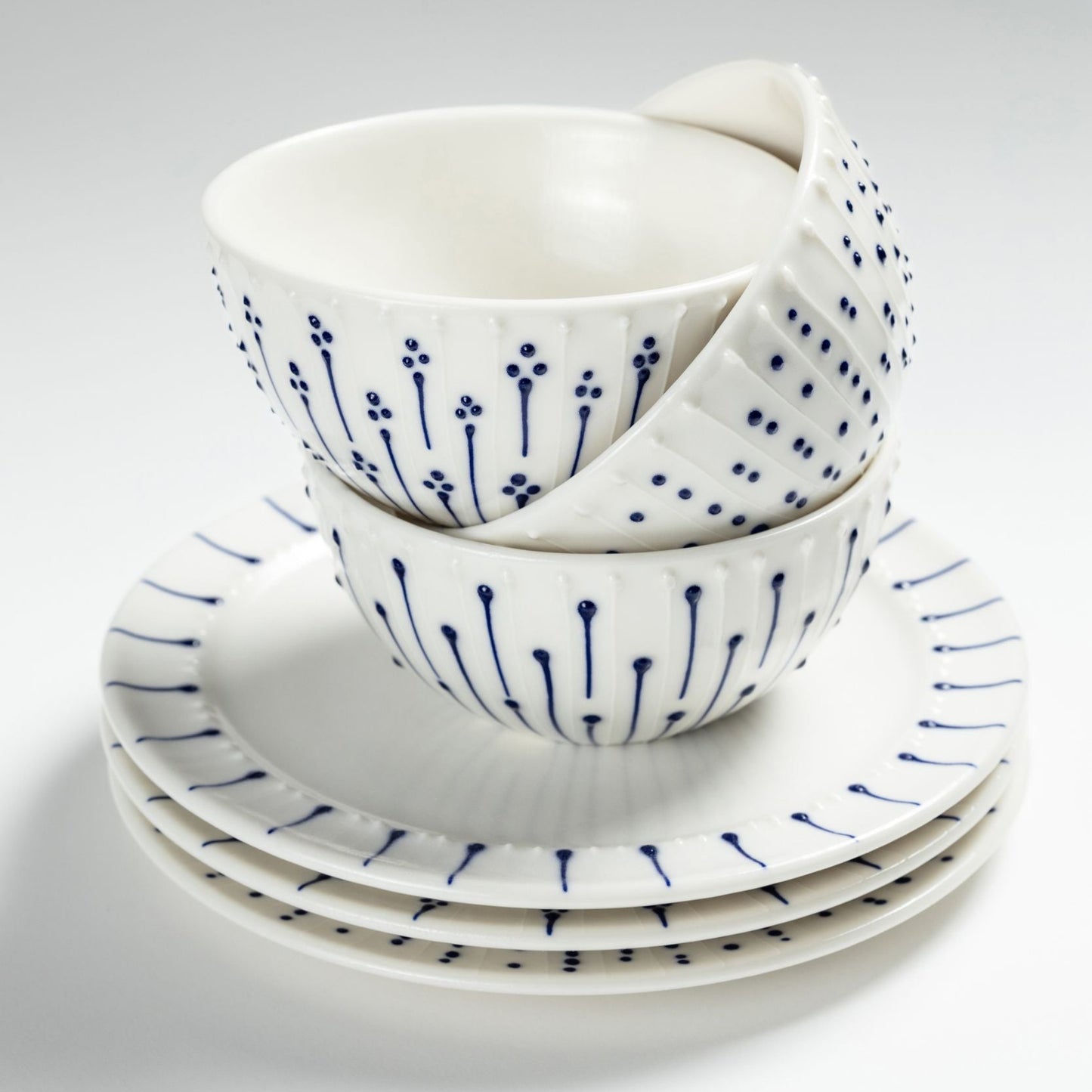 Stacked handmade porcelain breakfast bowls with blue slip-trailed decoration on matching porcelain side plates