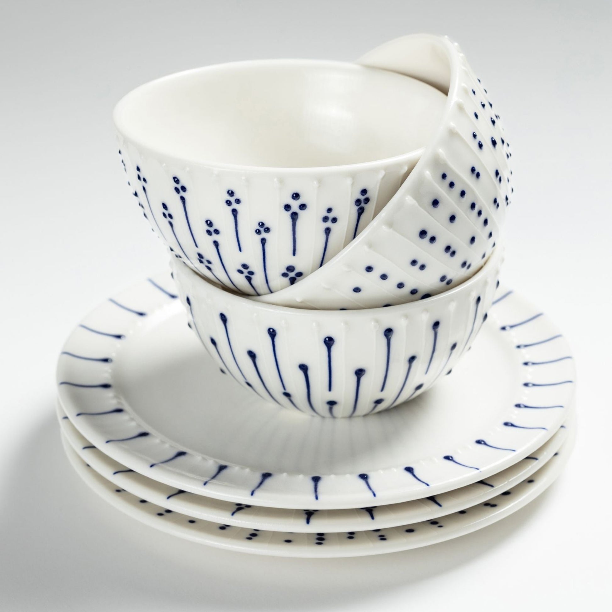 Stacked handmade porcelain breakfast bowls with blue slip-trailed decoration on matching porcelain side plates