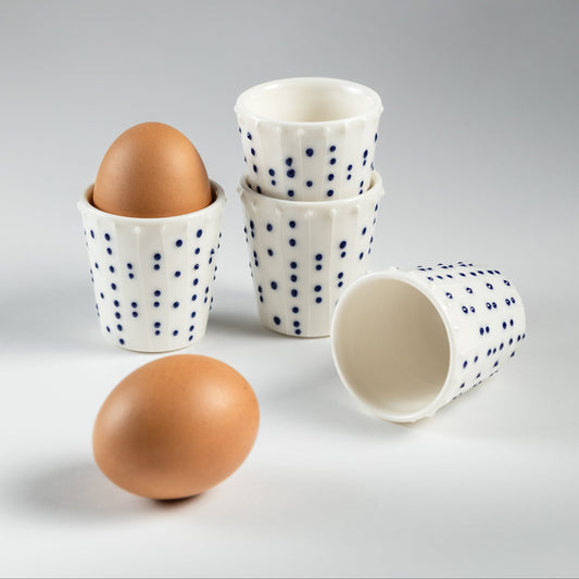 Handmade porcelain egg cups with blue slip-trailed dot decoration and eggs