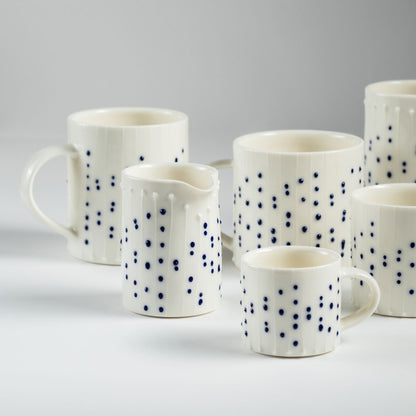 Handmade porcelain mugs and a small milk pourer with blue slip-trailed dot decoration