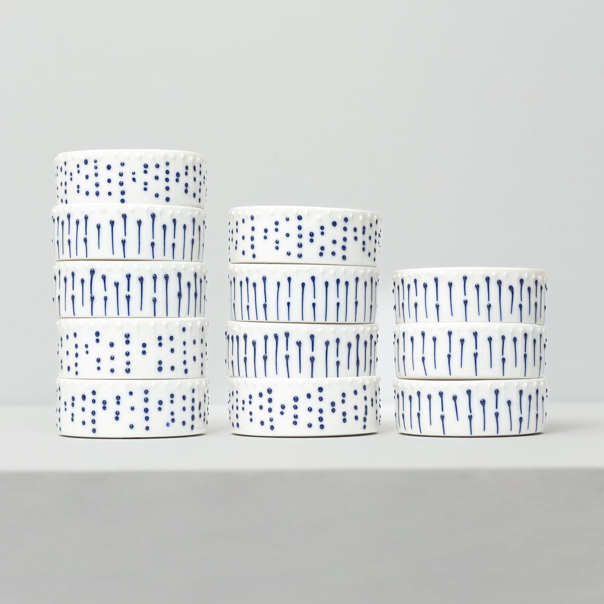 Stacked handmade porcelain ramekins with blue slip-trailed dot and line decoration