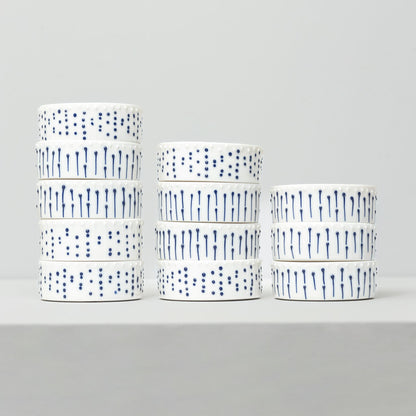 Stacked handmade porcelain ramekins with blue slip-trailed dot and line decoration