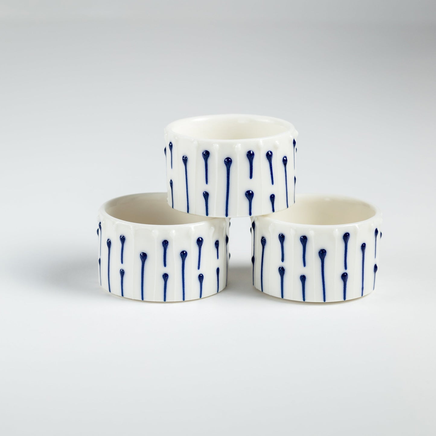 Handmade porcelain tealight holders with blue slip-trailed line decoration.