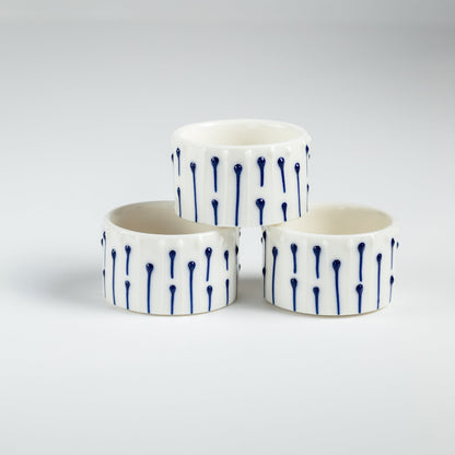 Handmade porcelain tealight holders with blue slip-trailed line decoration.