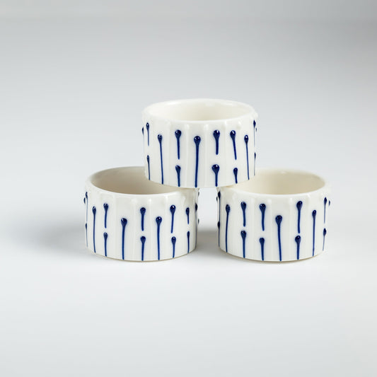 Handmade porcelain tealight holders with blue slip-trailed line decoration.