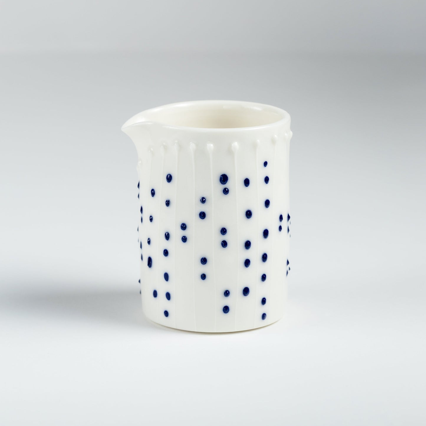 Handmade porcelain milk pourer with blue slip-trailed dot decoration