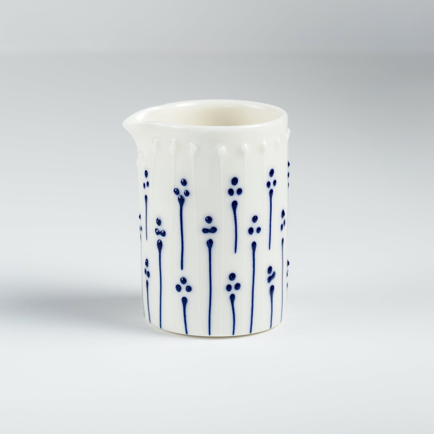 Handmade porcelain milk pourer with blue slip-trailed floral decoration