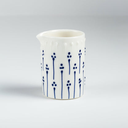 Handmade porcelain milk pourer with blue slip-trailed floral decoration
