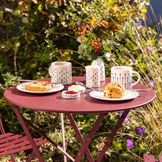 Garden table setting with handmade porcelain mugs and tableware with blue slip-trailed decoration