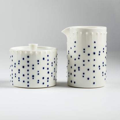 Handmade porcelain lidded jar and tall milk pourer with blue slip-trailed dot pattern