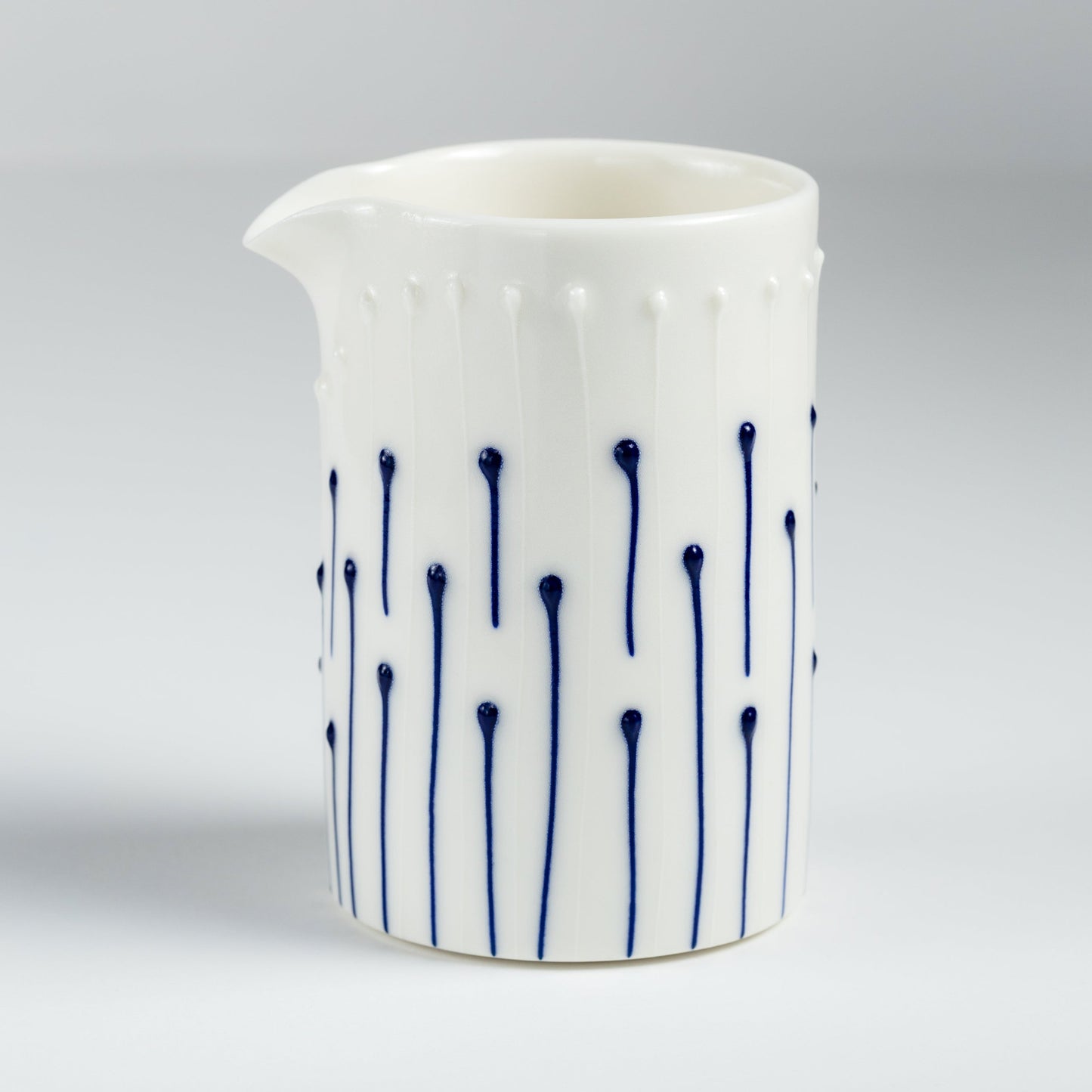 Handmade porcelain milk pourer with blue slip-trailed line pattern