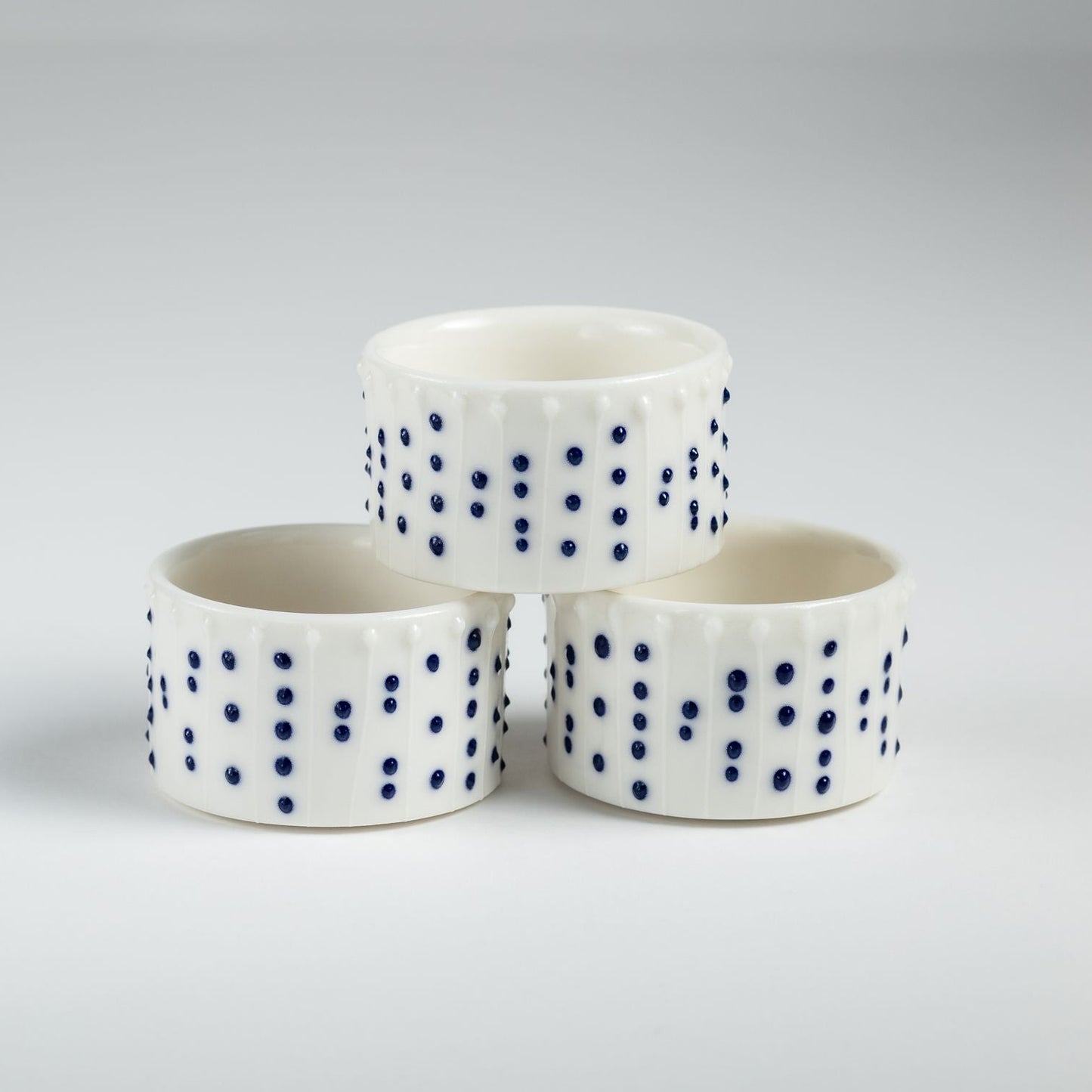 Handmade porcelain tealight holders with blue slip-trailed dot decoration.