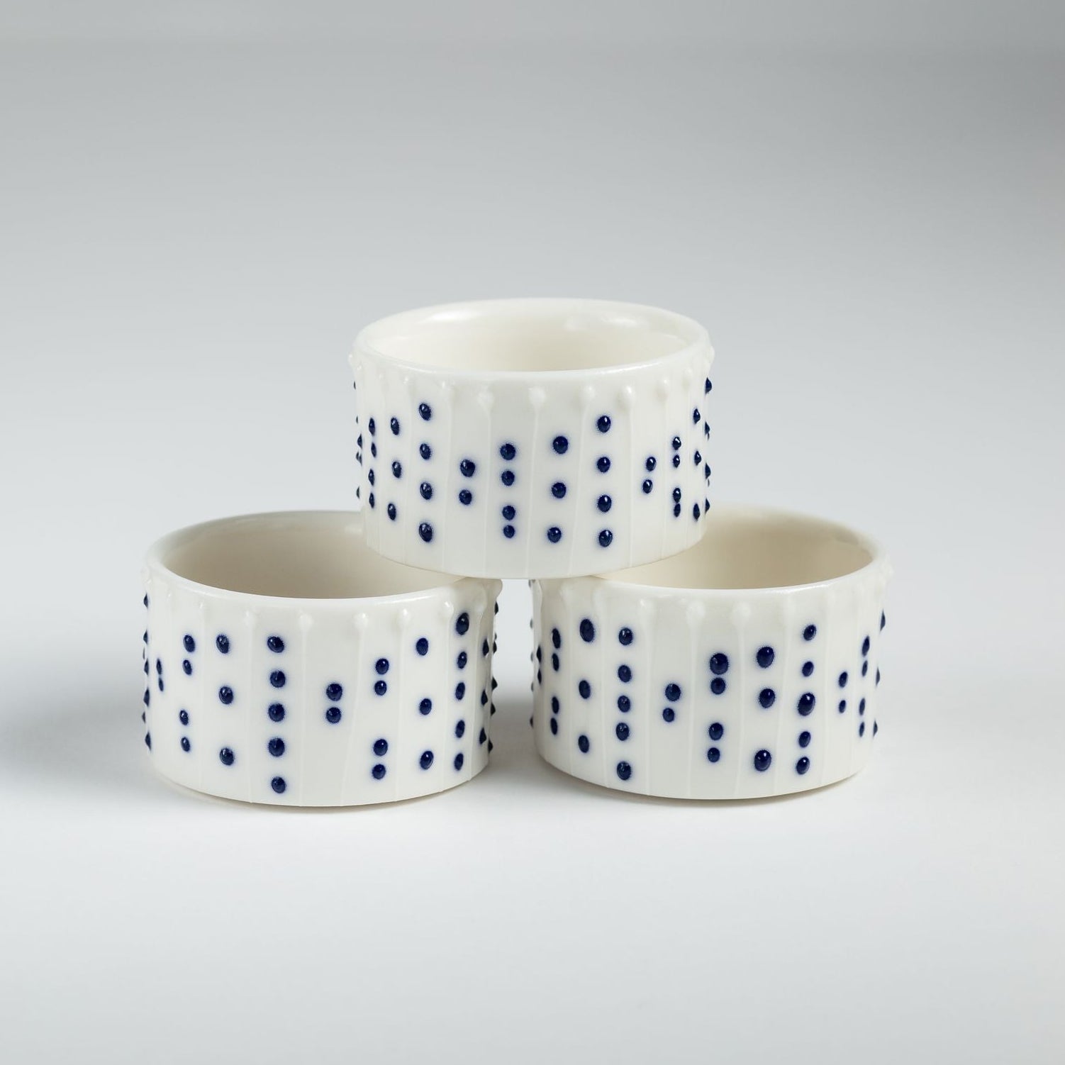 Handmade porcelain tealight holders with blue slip-trailed dot decoration.