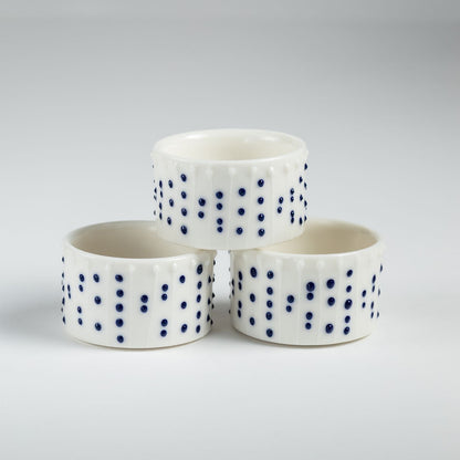 Handmade porcelain tealight holders with blue slip-trailed dot decoration.