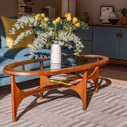 Handmade porcelain flower vase with blue dot decoration on a mid-century wooden coffee table, holding a large arrangement of yellow roses and eucalyptus.