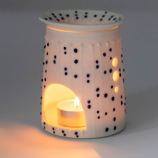Handmade porcelain wax burner with blue slip-trailed dot decoration and lit tealight