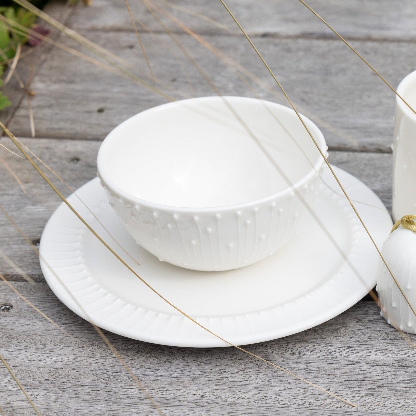 Handmade white porcelain mug, breakfast bowl and side plate on a rustic wooden table