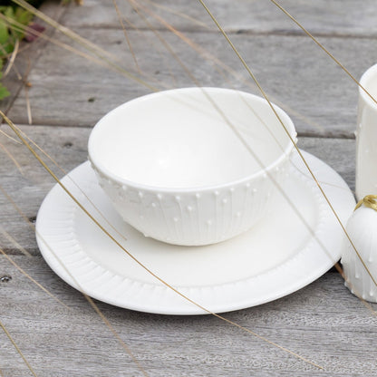 Handmade white porcelain mug, breakfast bowl and side plate on a rustic wooden table